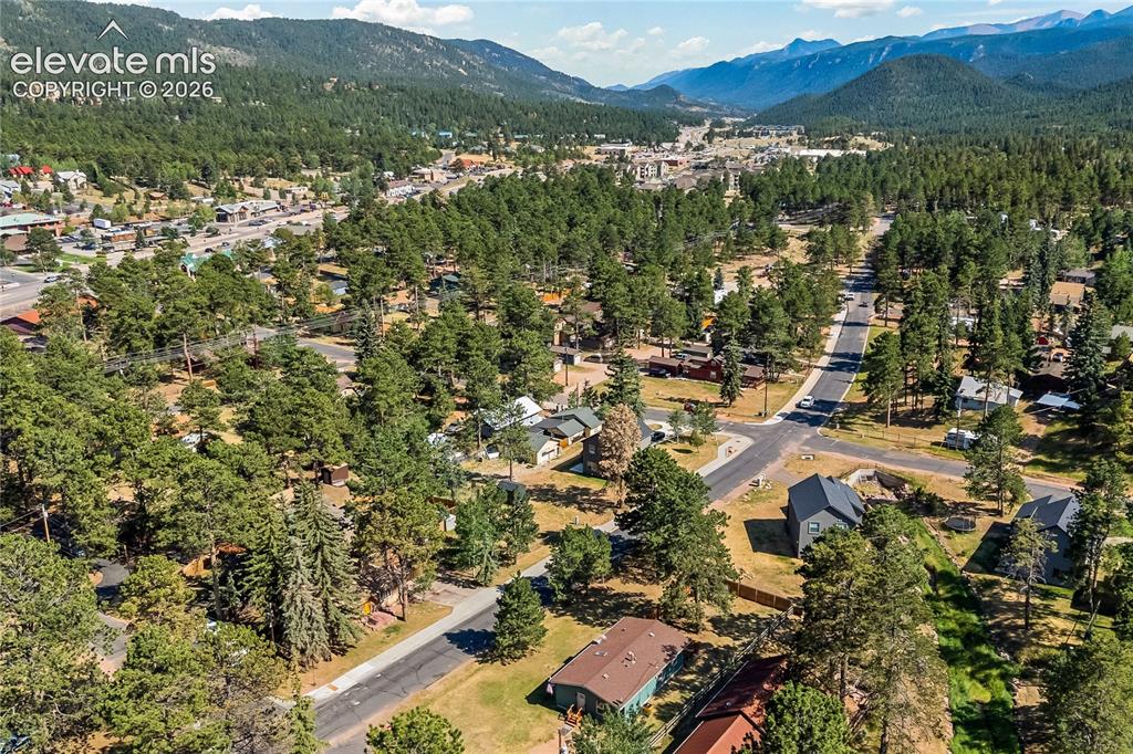 Image 5 of 32: Aerial perspective of a mountain town featuring a dense evergreen forest an