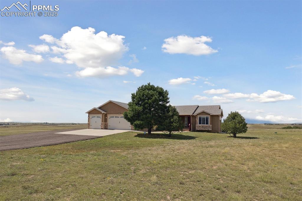 Image 3 of 42: Ranch-style house with concrete driveway, a rural view, a front lawn, an at