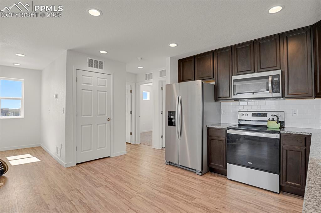 Image 8 of 24: Kitchen featuring dark brown cabinets, appliances with stainless steel fini
