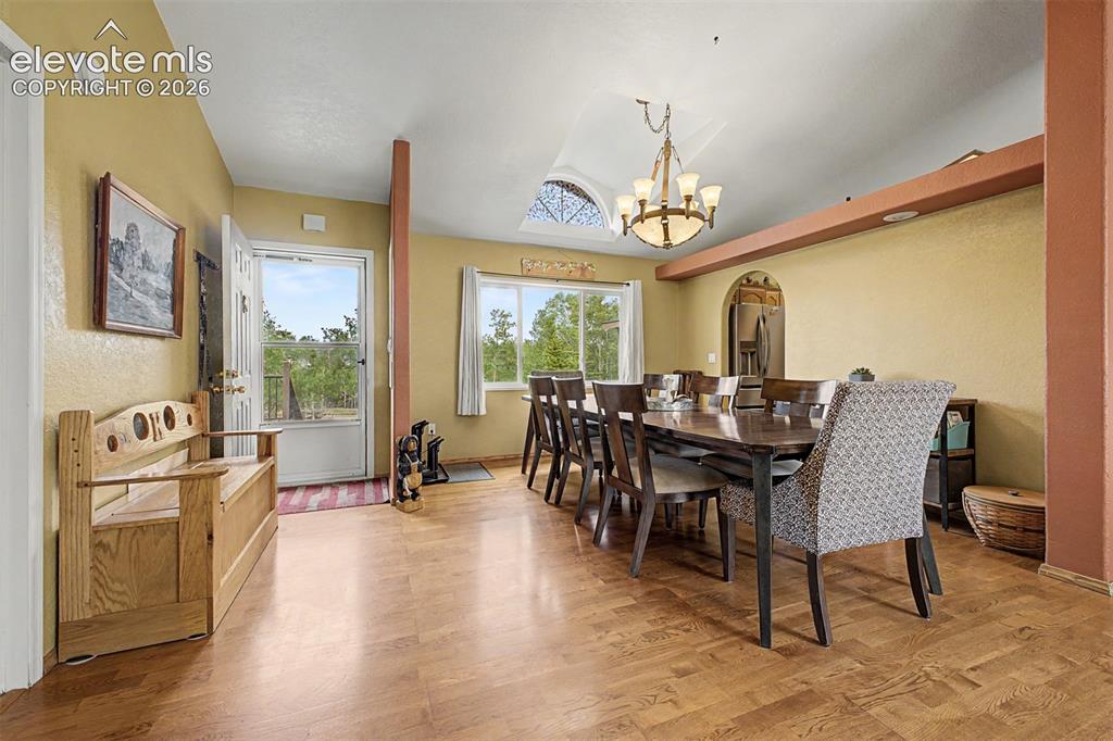 Image 11 of 48: Wood-finish flooring, vaulted ceiling, arched window, and chandelier