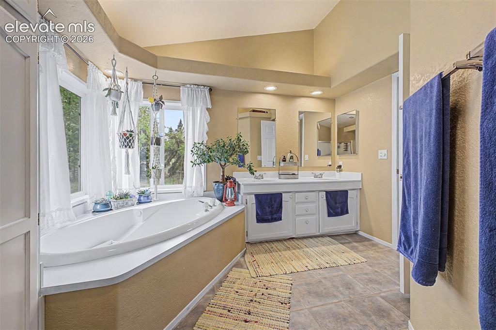 Image 18 of 48: Soaking tub with a tiled surround, dual vanity with undermount sinks, and t