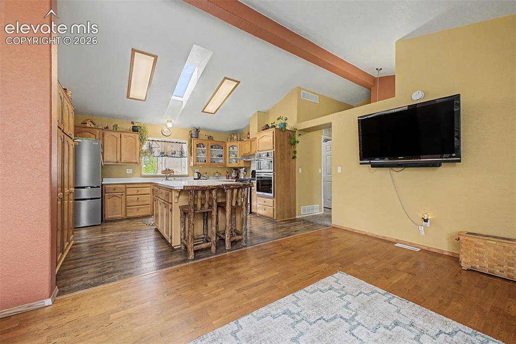 Image 22 of 48: Kitchen featuring wood cabinetry, stainless steel refrigerator, kitchen isl