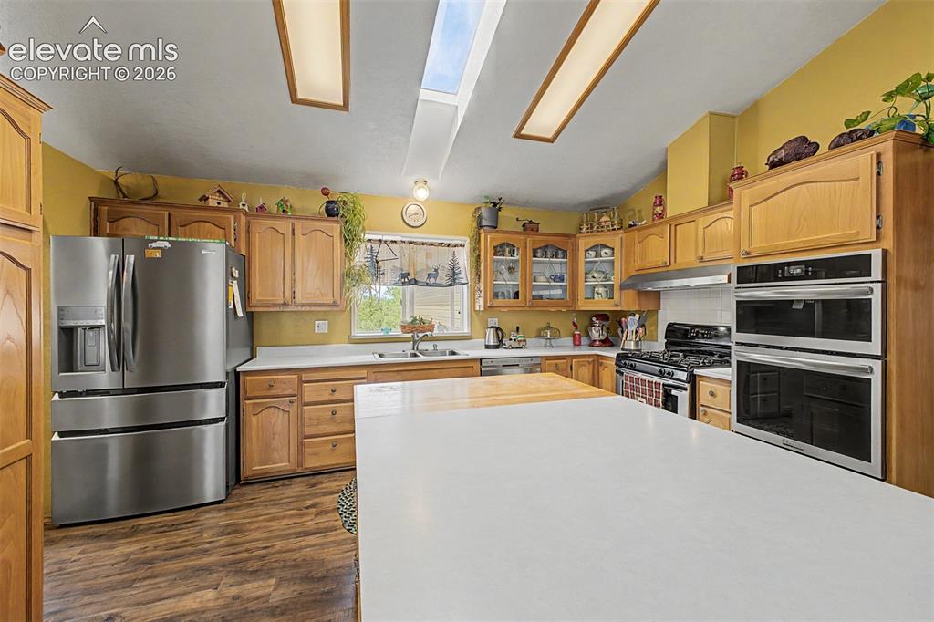 Image 24 of 48: Kitchen featuring wood-finish flooring, stainless steel appliances, extensi