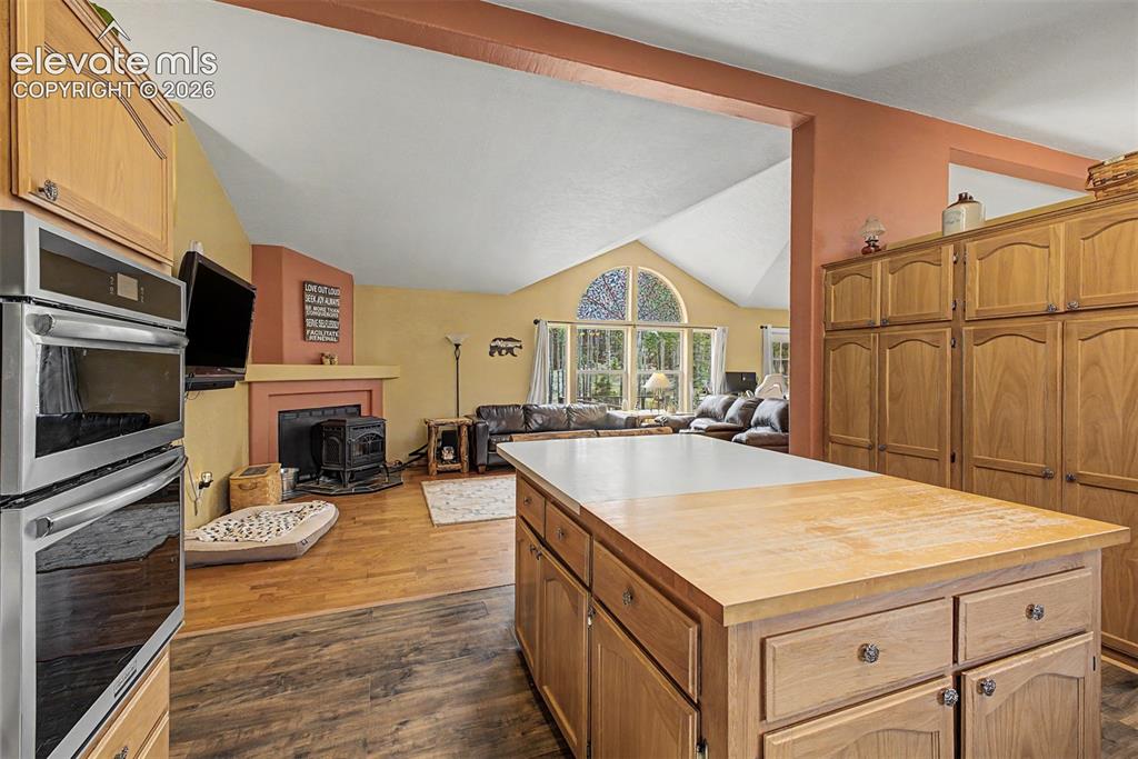 Image 25 of 48: Kitchen island with a light wood-finish countertop, wood-finish cabinetry, 