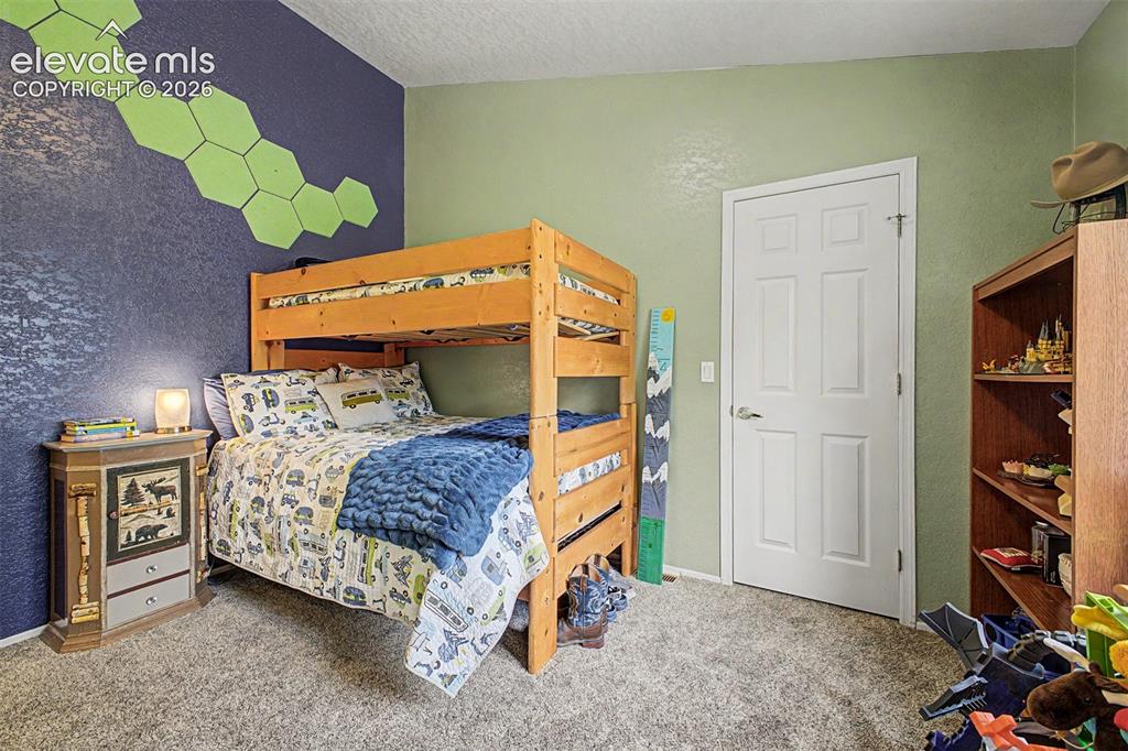 Image 28 of 48: Textured accent wall, wood-finish bunk bed, paneled interior door, built-in