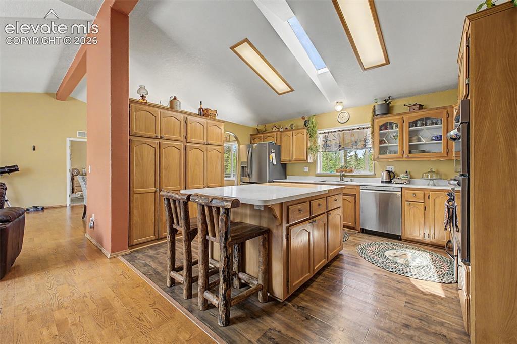 Image 41 of 48: Vaulted ceiling with skylights, wood-finish flooring, kitchen island with c