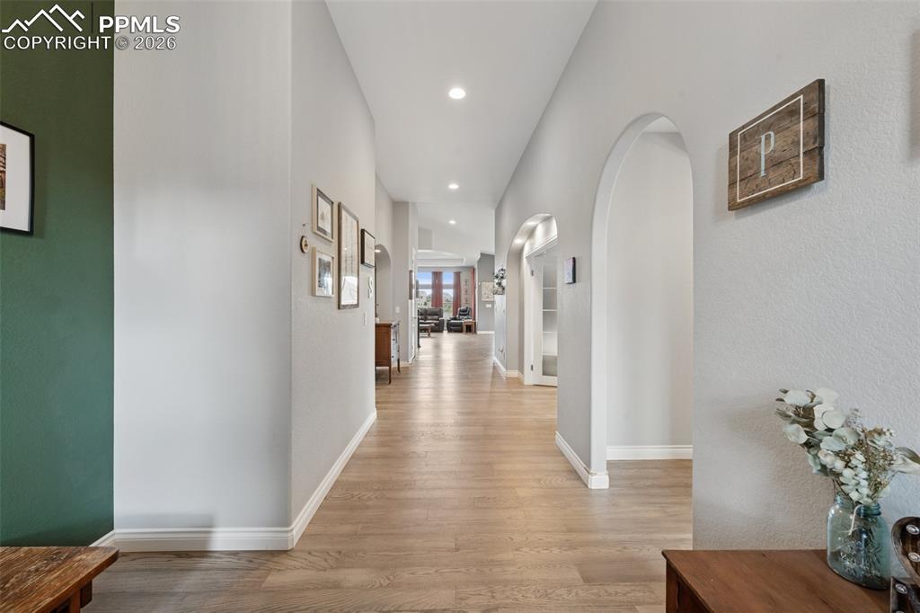 Image 11 of 46: Hall featuring light wood-type flooring, arched walkways, baseboards, and r
