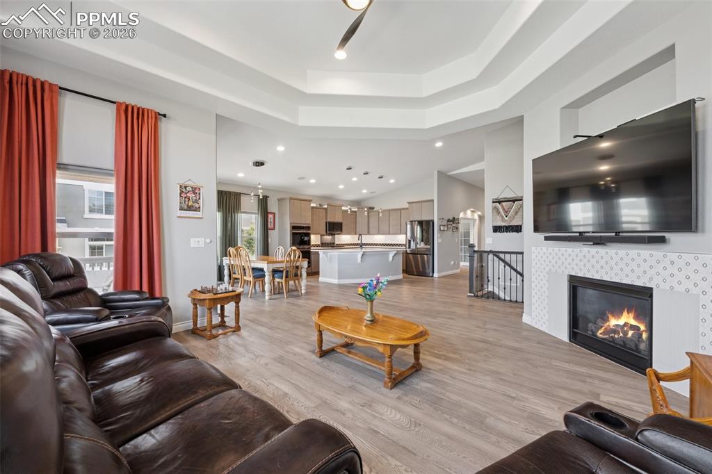 Image 13 of 46: Living room with light wood-style floors, a raised ceiling, recessed lighti