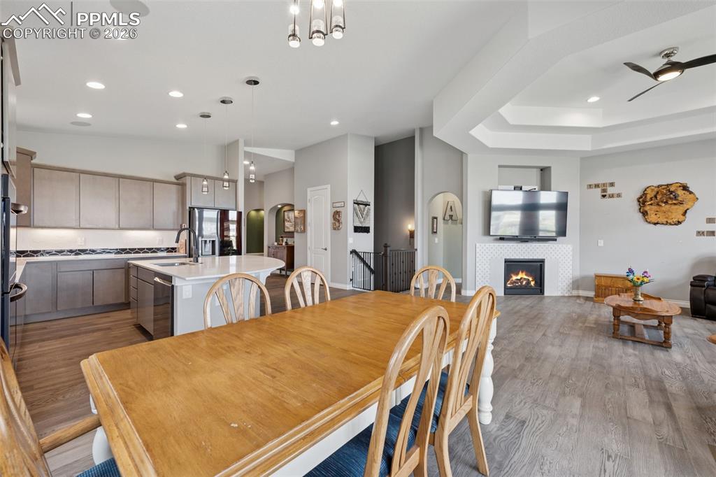 Image 15 of 46: Dining area with light wood-style floors, recessed lighting, a tiled firepl