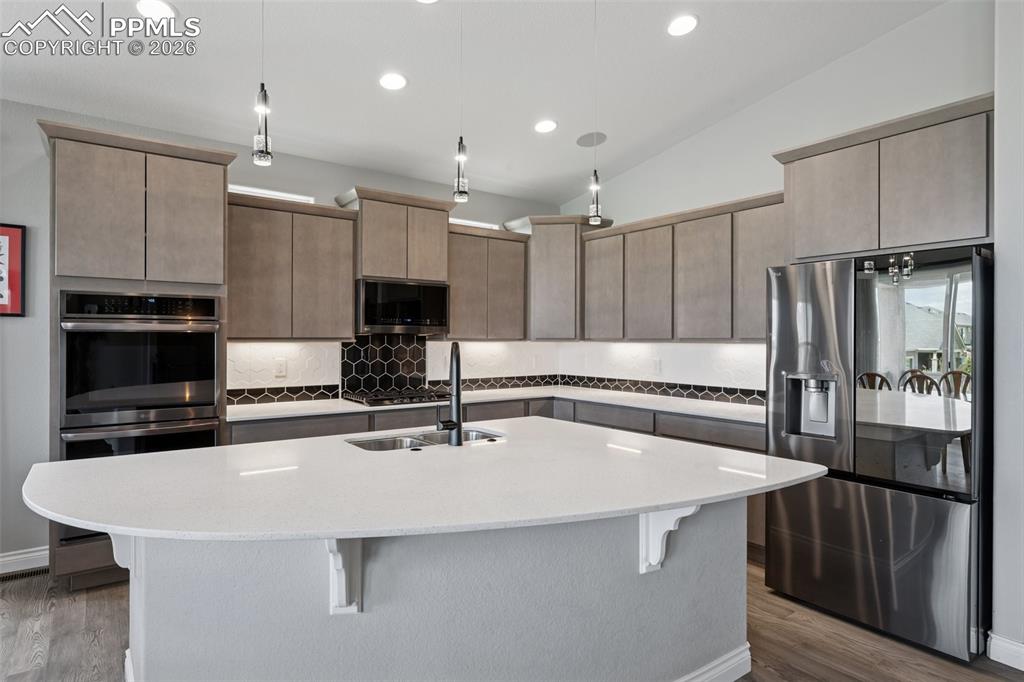 Image 16 of 46: Kitchen featuring black stainless appliances, a kitchen bar, decorative bac