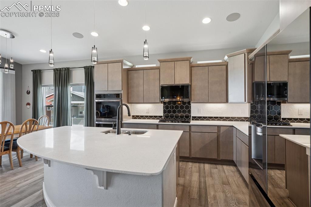 Image 18 of 46: Kitchen with a sink, appliances with black stainless finishes, light wood f