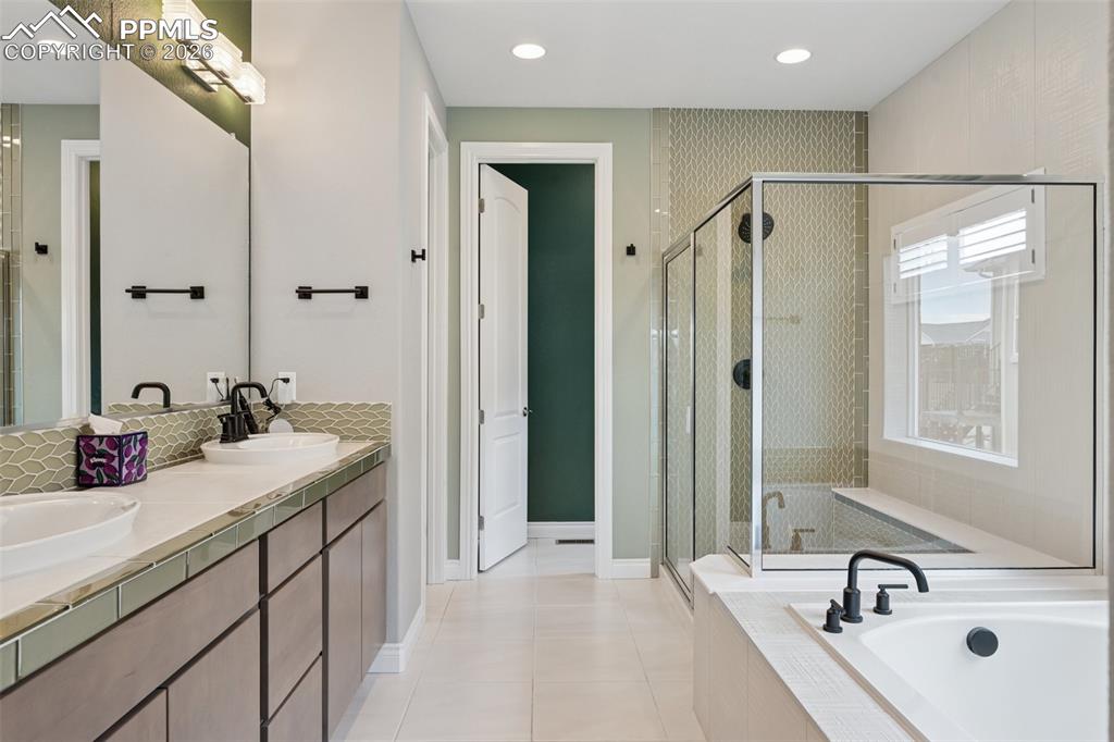 Image 22 of 46: Bathroom featuring a bath, a stall shower, tile patterned floors, double va