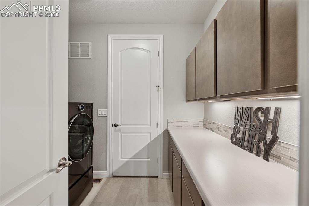 Image 26 of 46: Washroom with cabinet space, light wood-style flooring, baseboards, and was