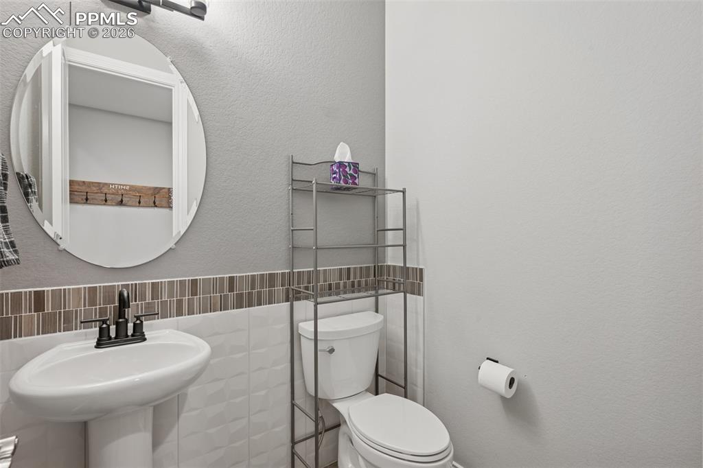 Image 27 of 46: Bathroom featuring toilet, tile walls, and a sink