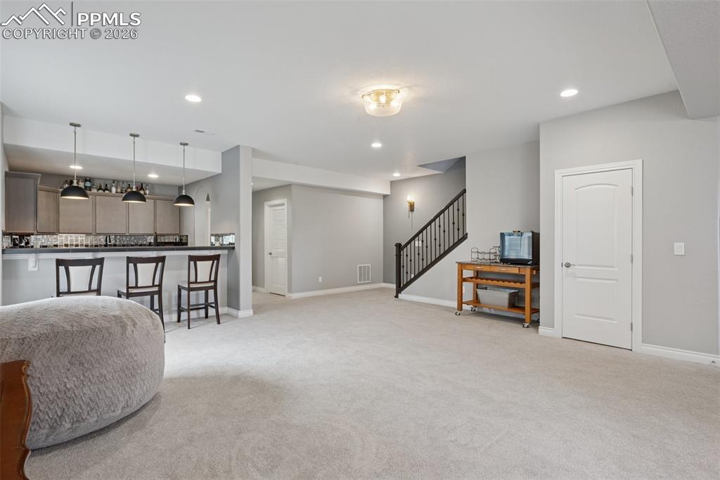 Image 33 of 46: Living room featuring light carpet, recessed lighting, stairs, and baseboar