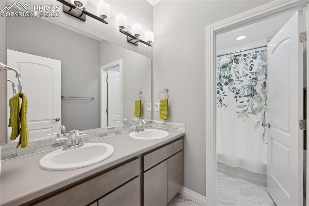 Image 43 of 46: Bathroom with marble finish flooring, double vanity, and shower / bathtub c