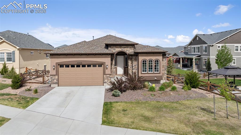 Image 5 of 46: View of front of property with stone siding, an attached garage, stucco sid