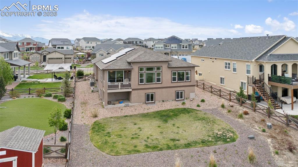 Image 8 of 46: Back of property featuring a residential view, stucco siding, a gate, solar