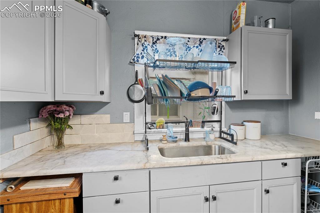 Image 11 of 18: Kitchen featuring light stone countertops and white cabinetry