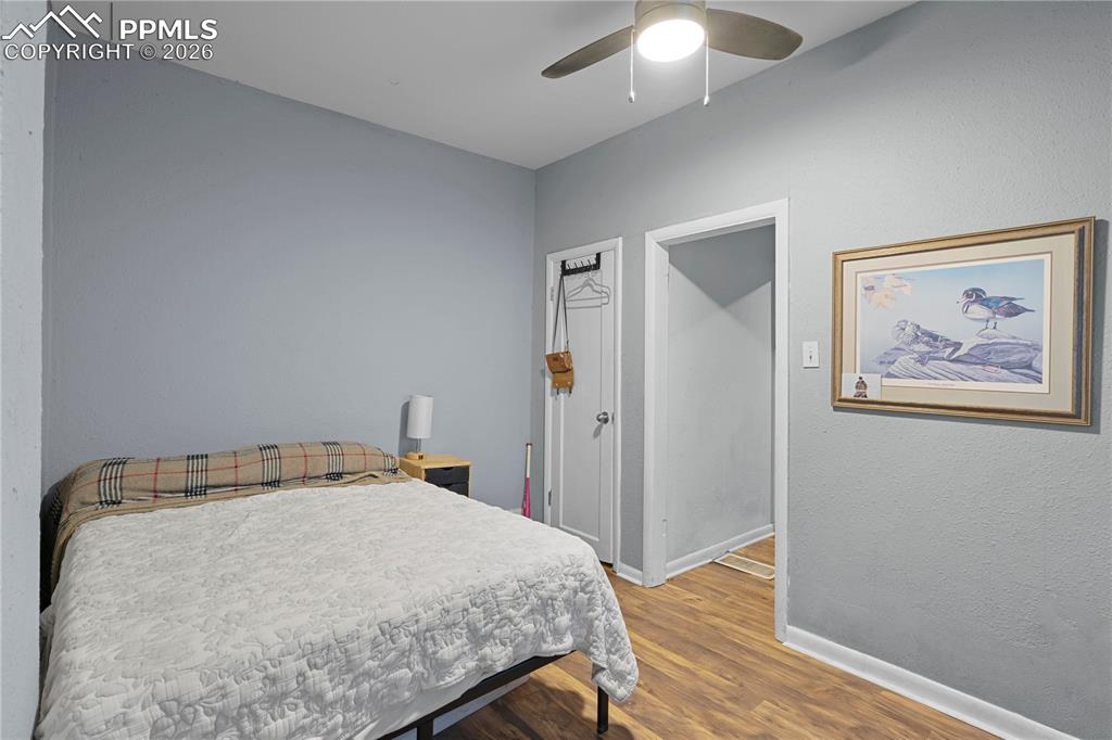 Image 16 of 18: Bedroom with wood finished floors, ceiling fan, and a textured wall