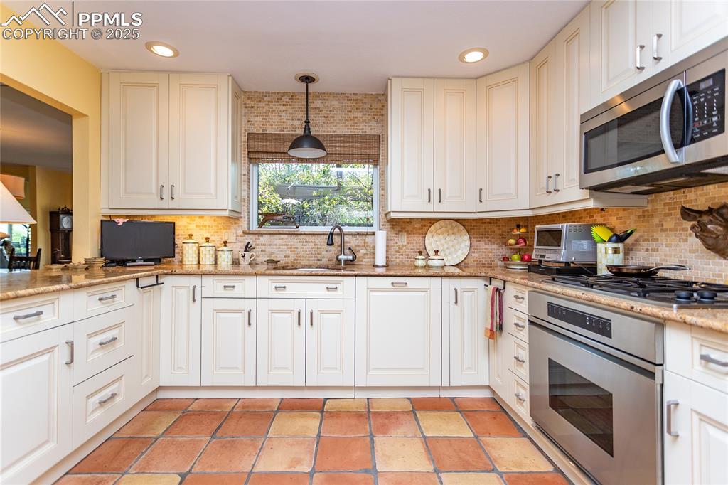 Image 13 of 46: Kitchen featuring appliances with stainless steel finishes, hanging light f