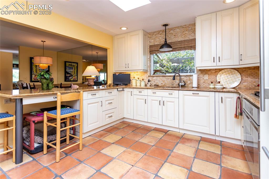 Image 14 of 46: Kitchen with decorative light fixtures, light stone countertops, recessed l