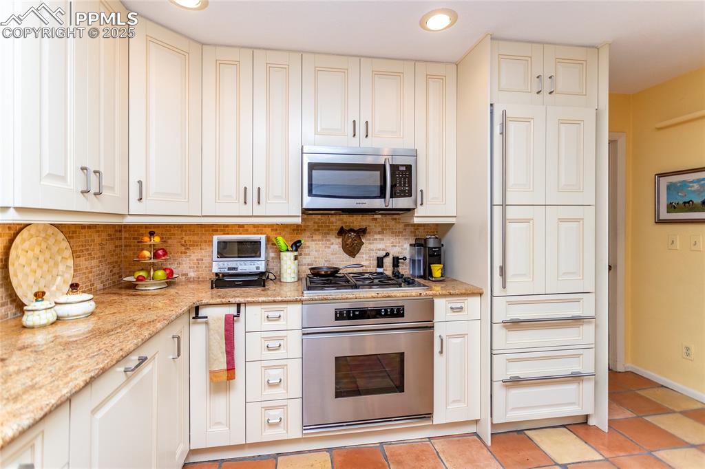 Image 15 of 46: Kitchen featuring stainless steel appliances, light stone countertops, deco