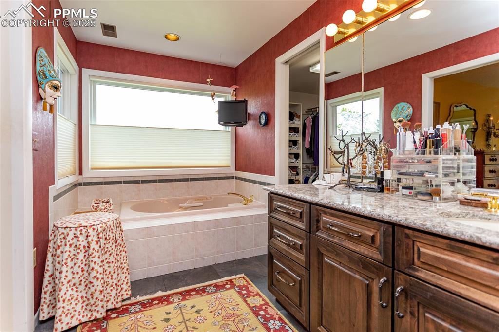 Image 20 of 46: Full bath with vanity, a garden tub, dark tile patterned floors, a spacious