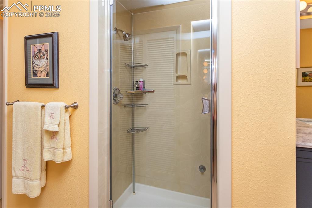 Image 25 of 46: Full bath with a textured wall, a stall shower, and vanity