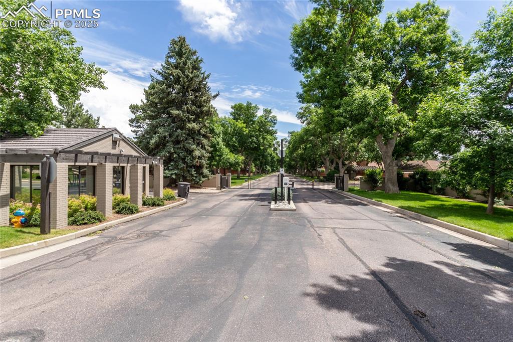 Image 44 of 46: View of asphalt street with a gated entry and curbs