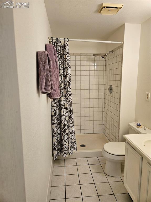 Image 21 of 35: Bathroom with a shower stall, vanity, and light tile patterned flooring