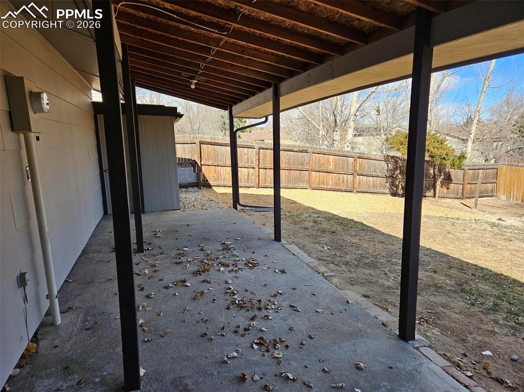 Image 27 of 35: Fenced backyard with a patio