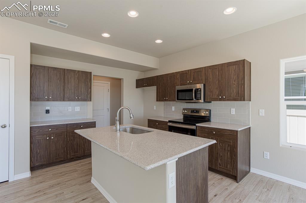 Image 5 of 26: Kitchen with appliances with stainless steel finishes, a sink, light wood f
