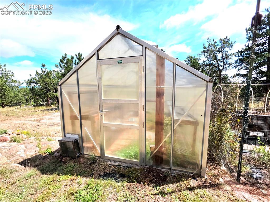 Image 35 of 50: Greenhouse outfitted with electricity, garden to the right. 