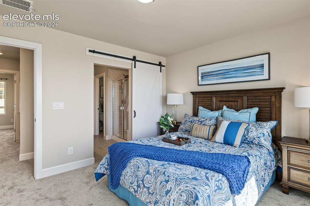 Image 3 of 34: Primary upstairs bedroom with sliding barn door to primary bathrom