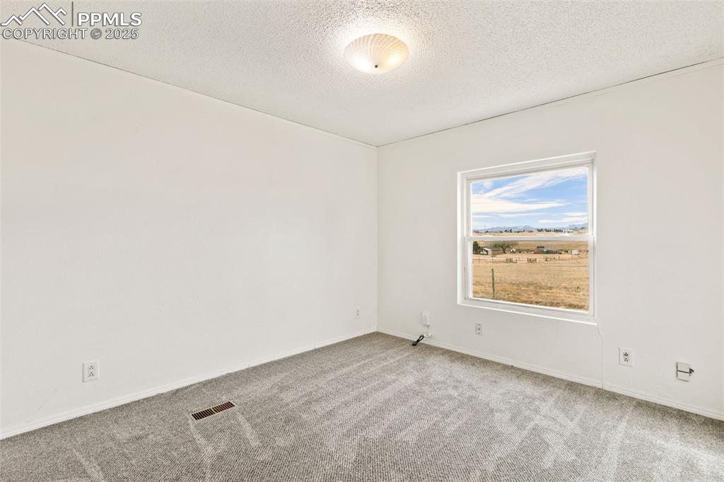 Image 27 of 50: secondary bedroom on main level with new carpet