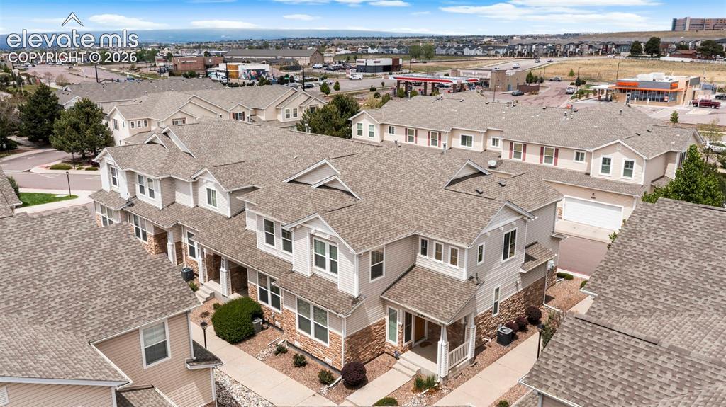 Image 11 of 30: Multi-story townhome with light-colored siding and stone accents