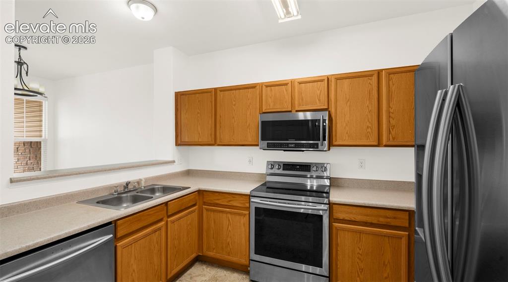 Image 17 of 30: Kitchen featuring wood-finish cabinetry, stainless steel appliances, a doub