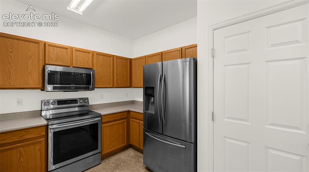 Image 19 of 30: Kitchen featuring wood cabinetry, stainless steel appliances, light counter