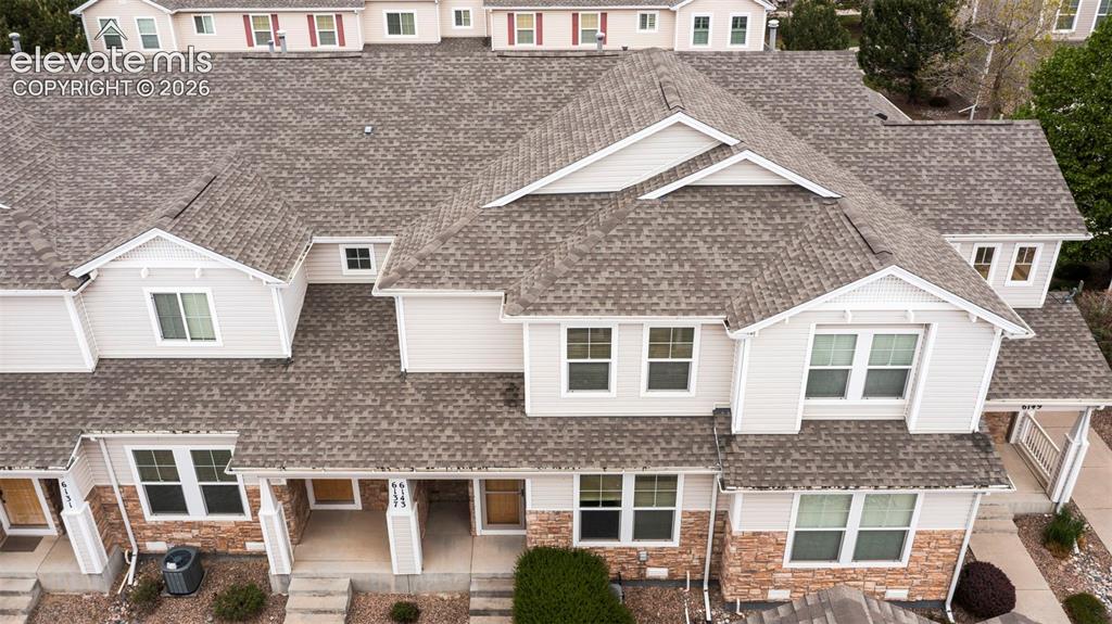 Image 2 of 30: Multi-level townhome exterior featuring light-colored siding, a stone facad