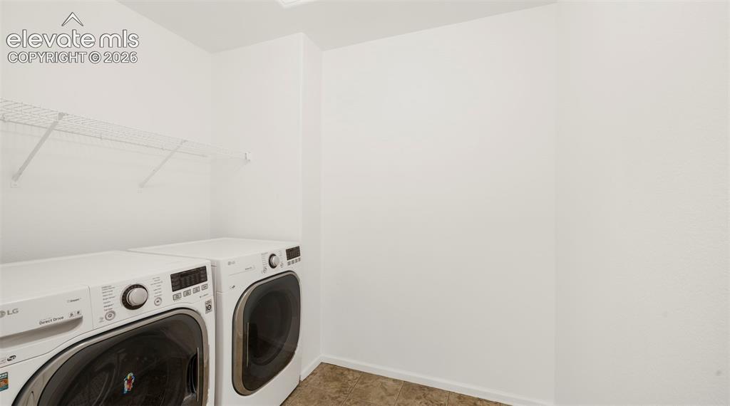 Image 24 of 30: Laundry area featuring white walls, wire shelving, and patterned floor tile