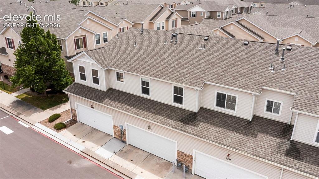Image 8 of 30: Multi-story townhouse featuring an attached two-car garage, light-colored s