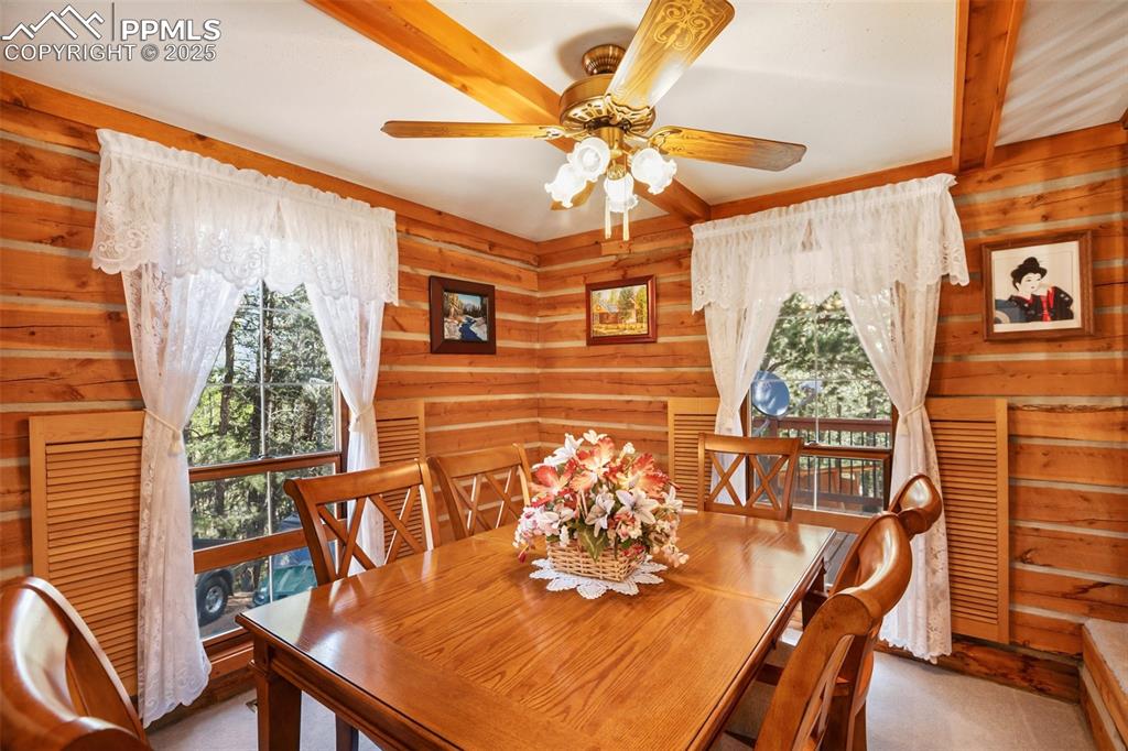 Image 13 of 36: Dining area with a ceiling fan and wood walls