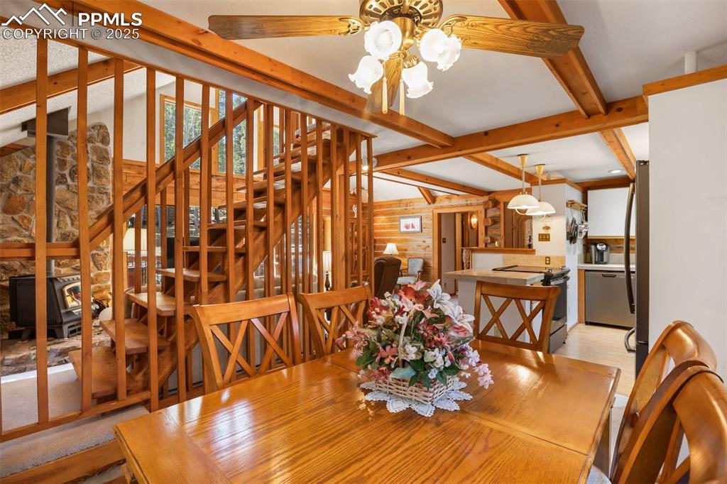 Image 15 of 36: Dining area featuring beamed ceiling, light wood-style flooring, and a chan