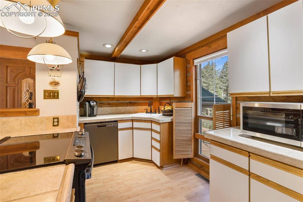 Image 17 of 36: Kitchen with dishwashing machine, a sink, light countertops, light wood-typ