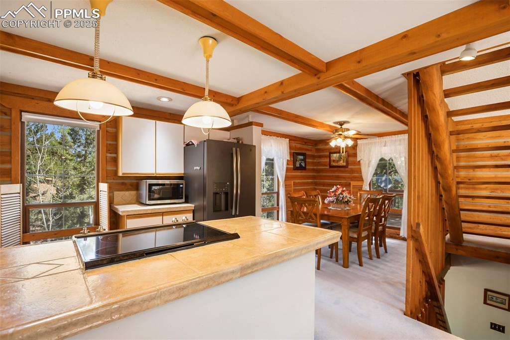 Image 19 of 36: Kitchen with stainless steel appliances, hanging light fixtures, beamed cei