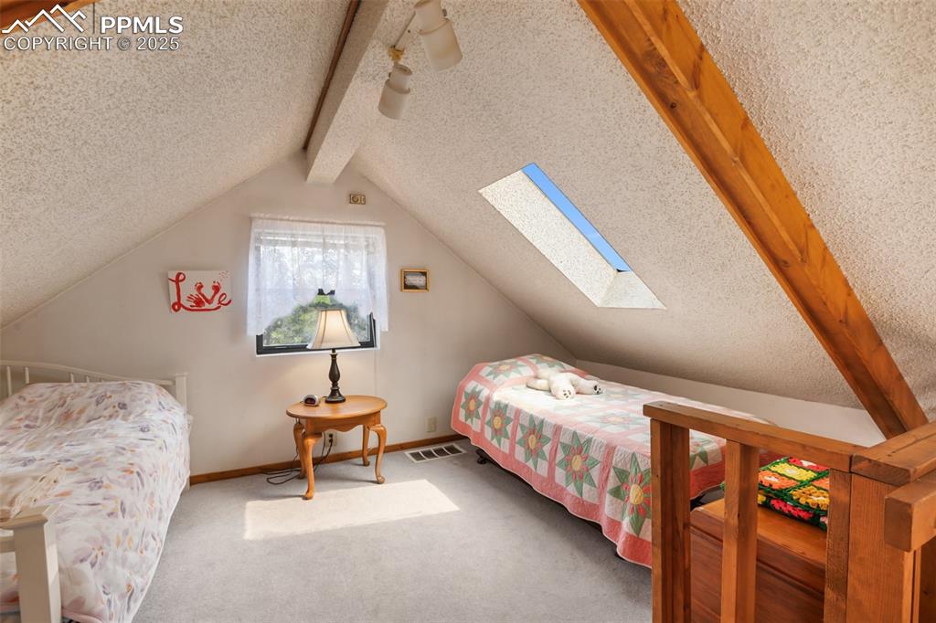 Image 23 of 36: Carpeted bedroom with a skylight, a textured ceiling, and baseboards