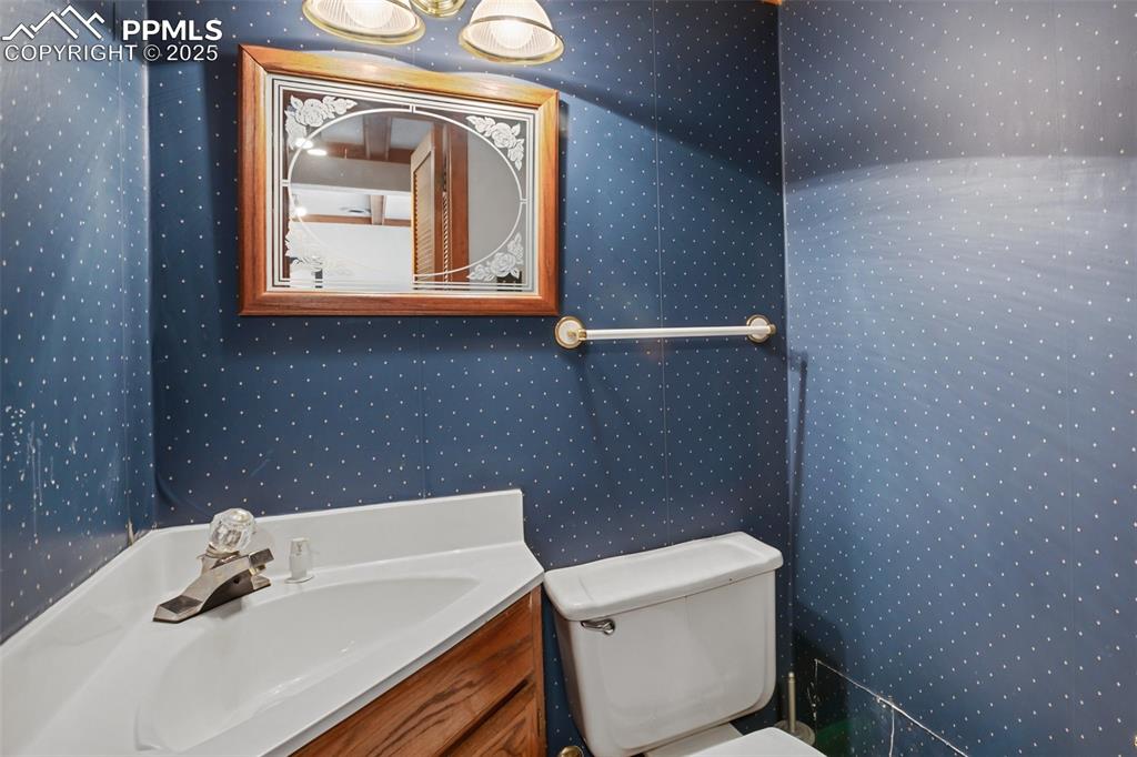 Image 27 of 36: Bathroom with wallpapered walls, toilet, and vanity