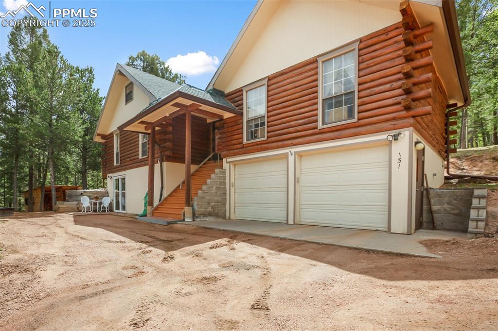Image 3 of 36: View of front of home featuring log siding, a garage, stairway, and drivewa