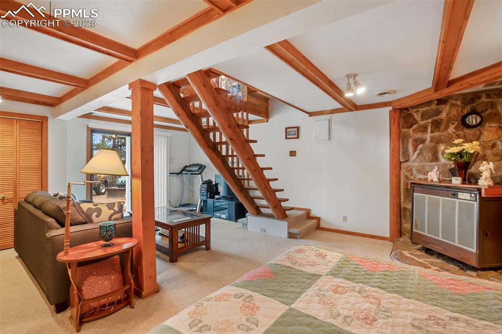 Image 30 of 36: Carpeted living area featuring stairway and beamed ceiling